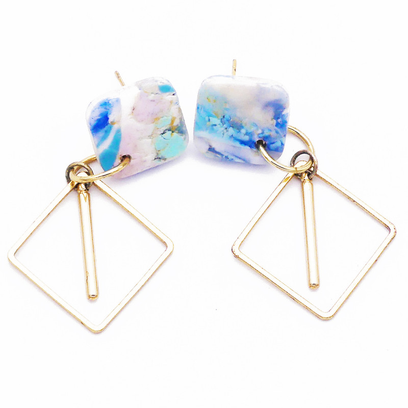 Boucles d'oreilles polymère de forme carré avec éléments dorés en losange. Couleurs bleu clair, bleu soutenu et rose pâle.